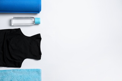 Stylish sportswear, bottle of water and yoga mat on white background, flat lay