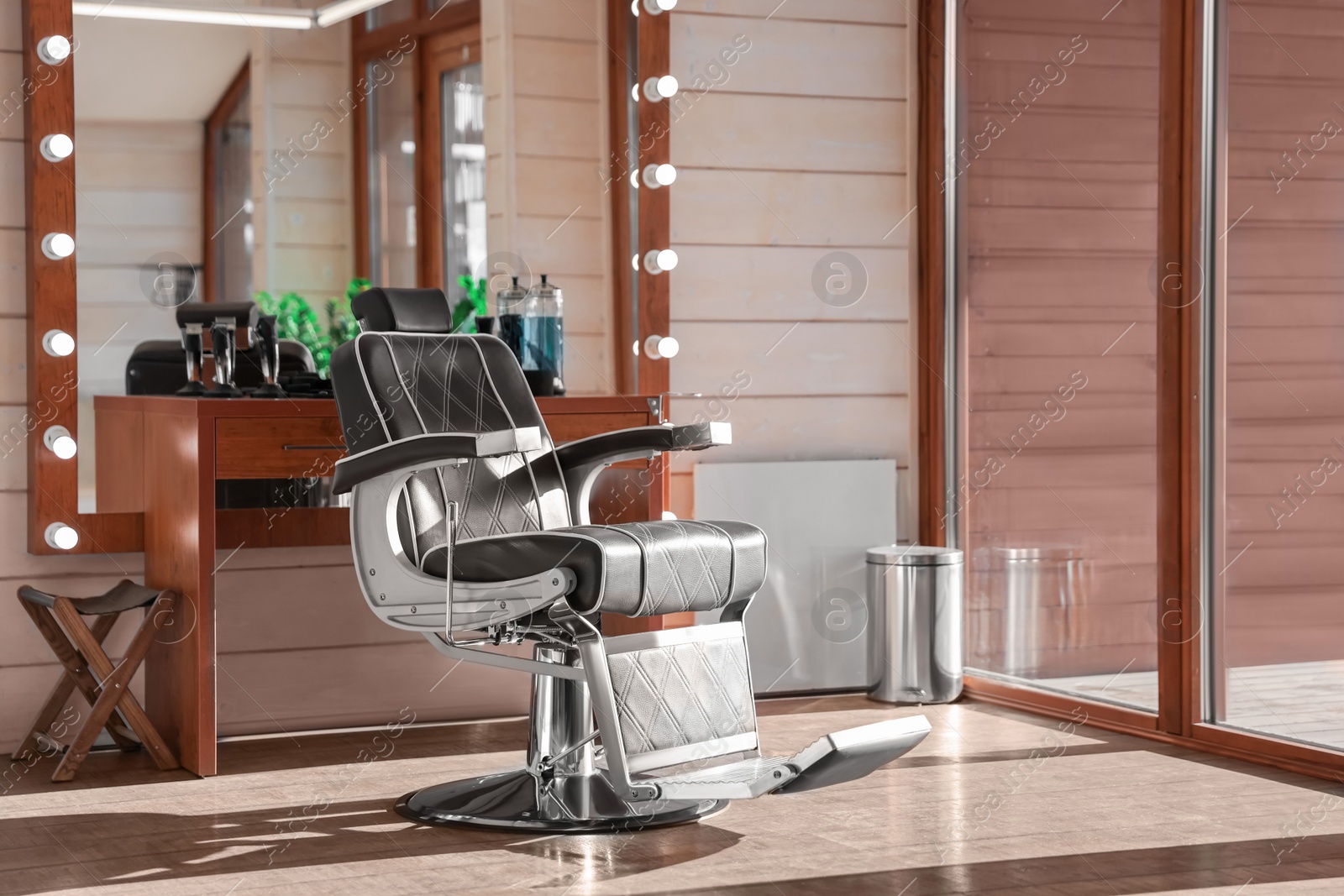 Photo of Stylish hairdresser's workplace with professional armchair and large mirror in barbershop. Interior design