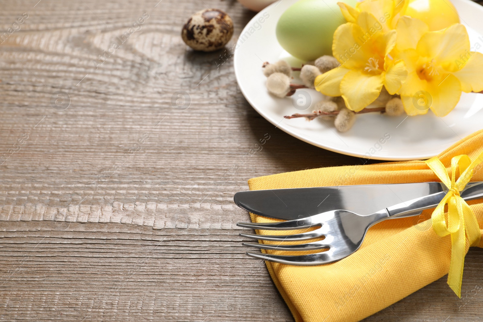 Photo of Festive Easter table setting with painted eggs and floral decor on wooden background, closeup. Space for text