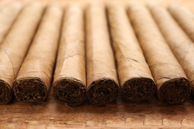 Photo of Many cigars on wooden table, closeup. Tobacco smoking