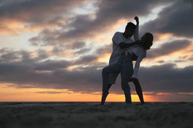 Photo of Happy couple dancing on beach at sunset