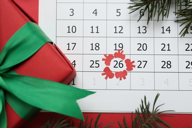 Gift on calendar with marked Boxing Day date, flat lay