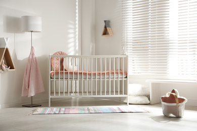 Photo of Cute baby room interior with crib and decor elements