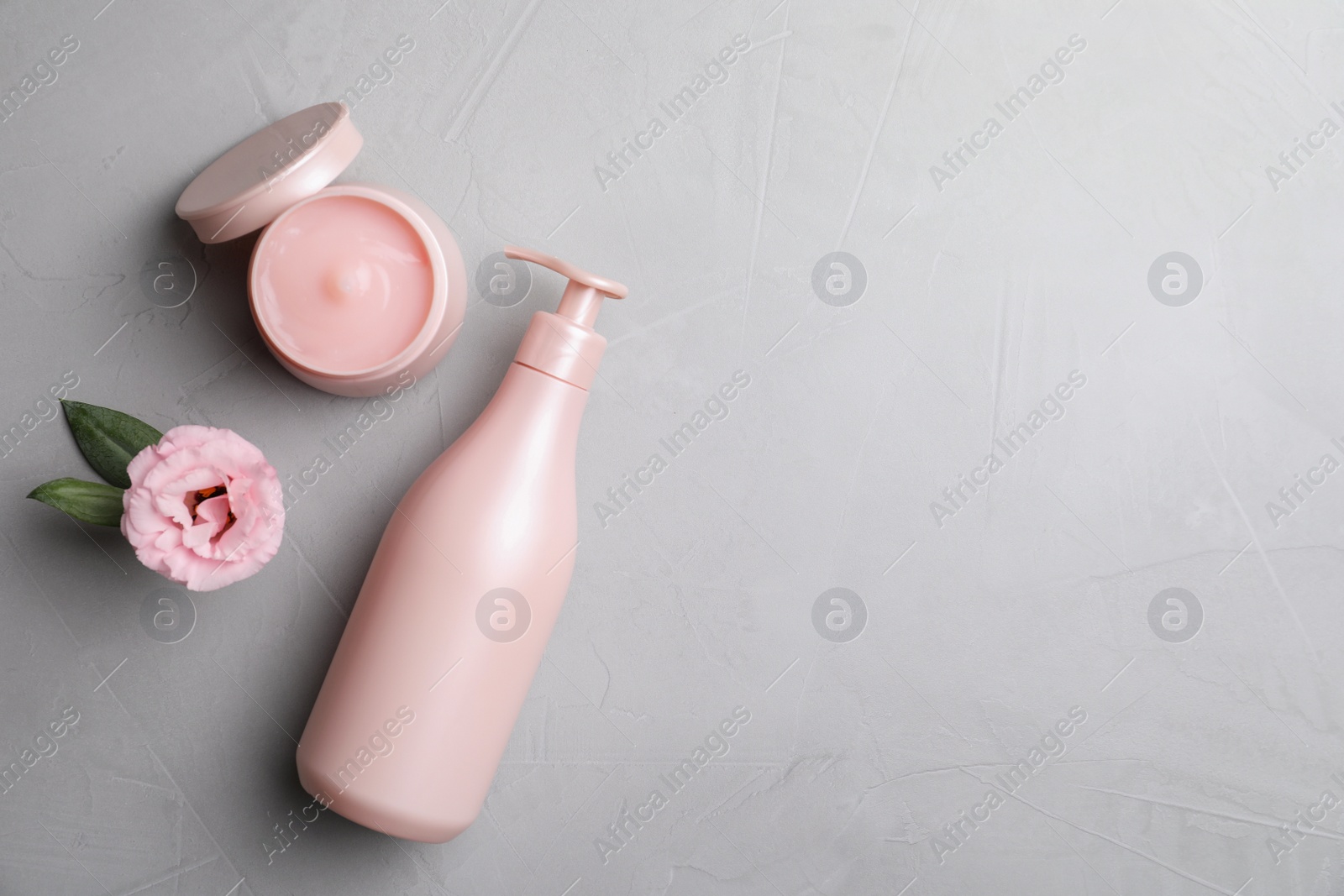 Photo of Hair cosmetic products and flower on grey stone table, flat lay. Space for text