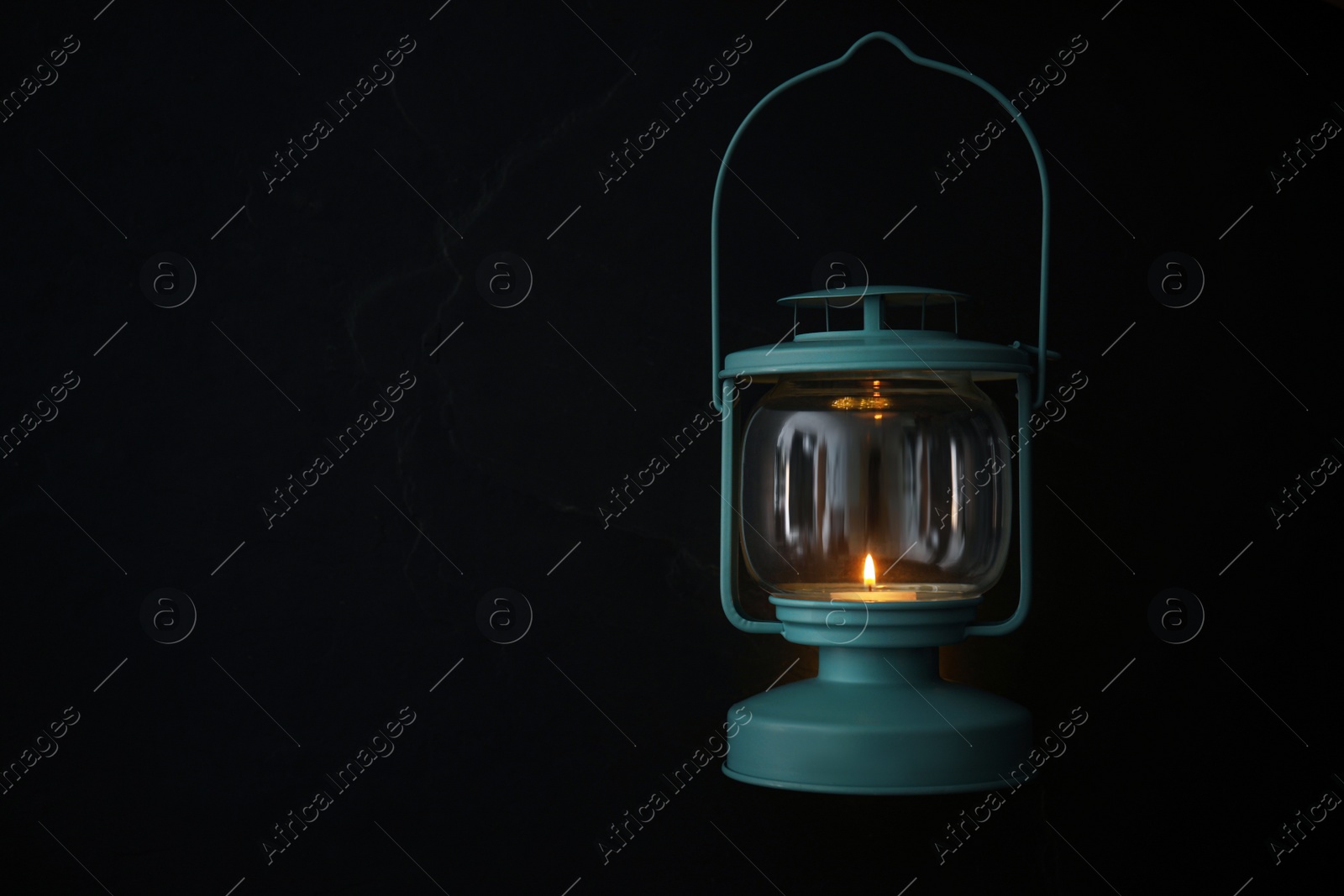 Photo of Vintage lantern with burning candle on black background. Space for text