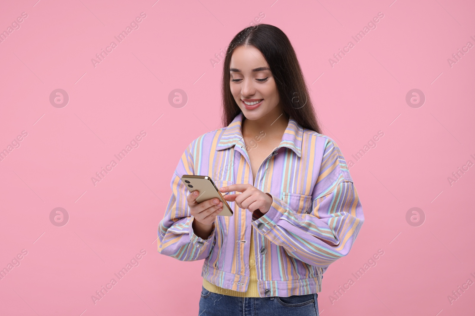 Photo of Happy woman sending message via smartphone on pink background