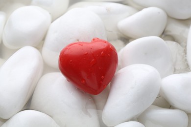 Photo of Red decorative heart on stones and water, closeup