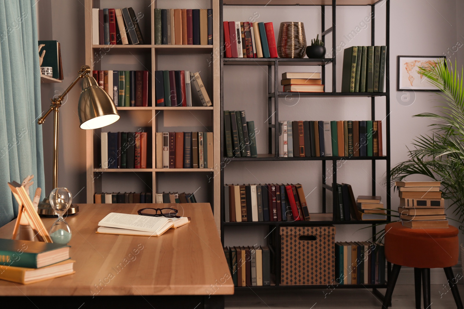 Photo of Wooden table and collection of different books on shelves in home library