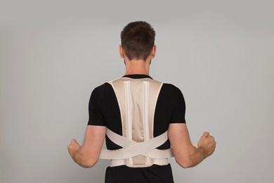 Photo of Man with orthopedic corset on grey background, back view