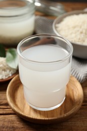 Photo of Glass of rice water on wooden table, closeup