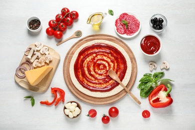 Photo of Flat lay composition with pizza crust and ingredients on white wooden table