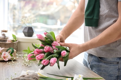 Photo of Male decorator creating beautiful bouquet at table