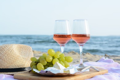 Photo of Glasses with rose wine and snacks for beach picnic on sandy seashore