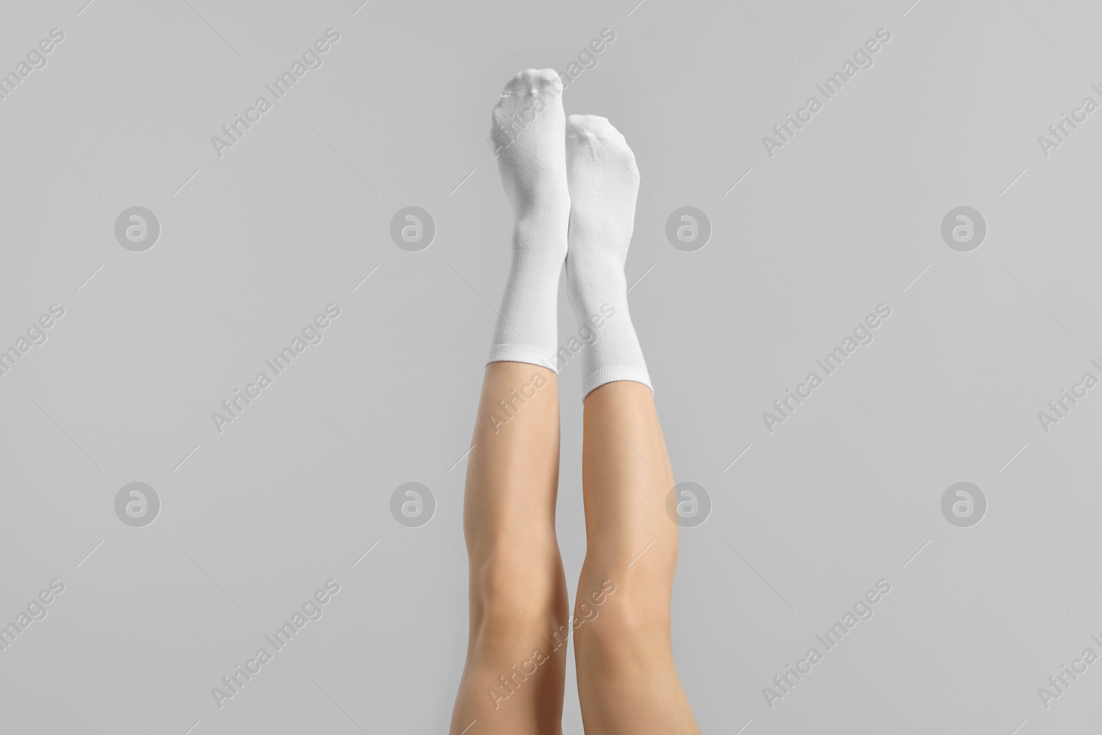 Photo of Woman in stylish white socks on light grey background, closeup