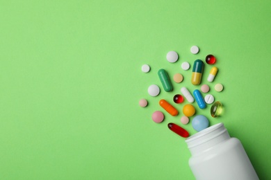 Bottle with different pills on color background, flat lay. Space for text