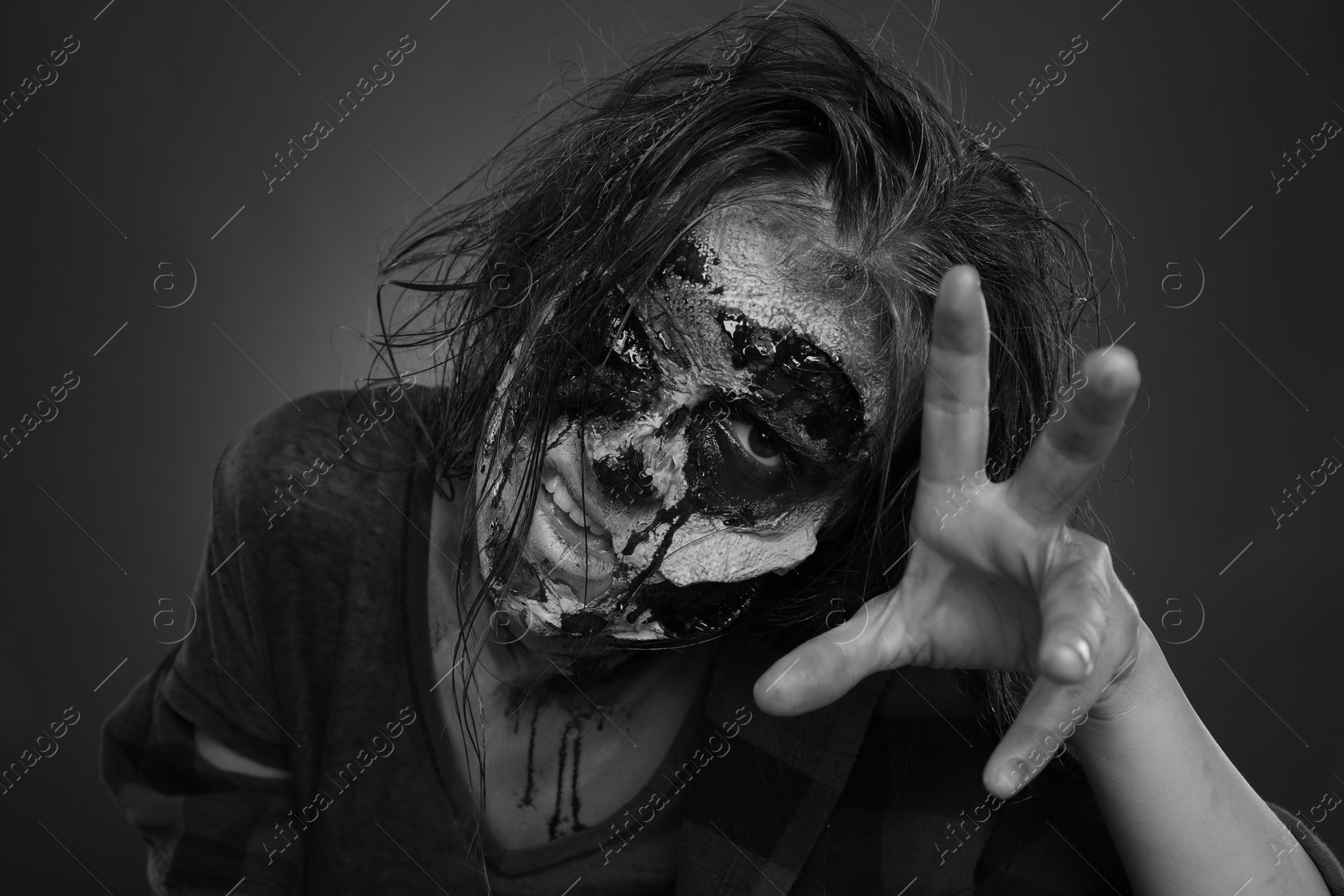 Photo of Scary zombie on dark background, black and white effect. Halloween monster