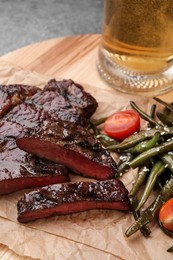 Mug with beer, delicious fried steak and asparagus on wooden table
