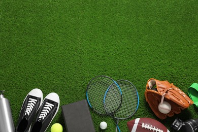 Photo of Different sports equipment on green grass, flat lay. Space for text