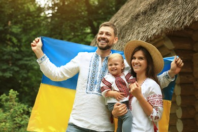 Photo of Happy family in national clothes with flag of Ukraine outdoors