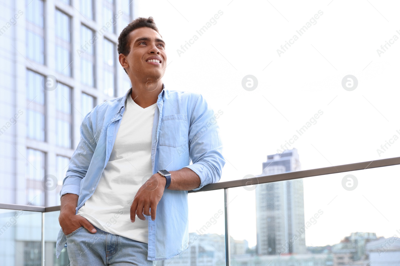 Photo of Handsome young African-American man on city street, low angle view. Space for text