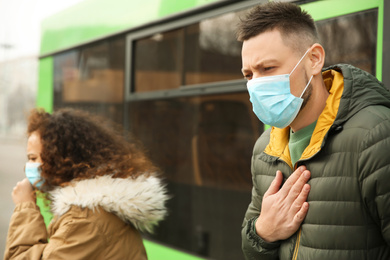 Photo of People with disposable masks near bus outdoors. Virus protection