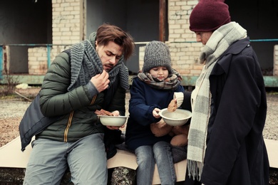 Photo of Poor young family with bread on dirty street
