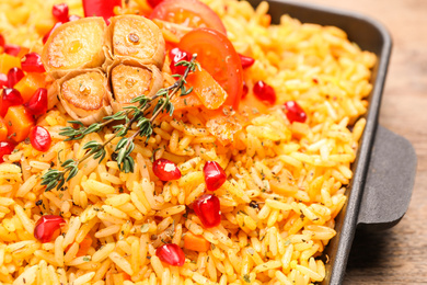 Photo of Tasty rice pilaf with vegetables on wooden table, closeup