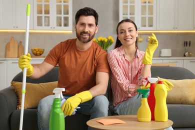 Photo of Spring cleaning. Lovely couple with mop and detergents in living room