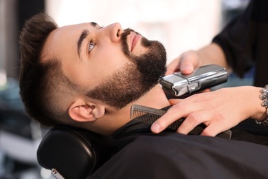 Professional hairdresser working with client in barbershop