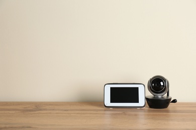 Photo of Baby monitors on wooden table, space for text. CCTV equipment