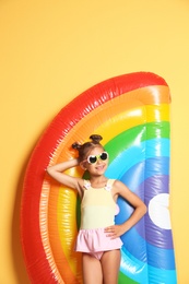 Cute little girl with inflatable mattress on color background