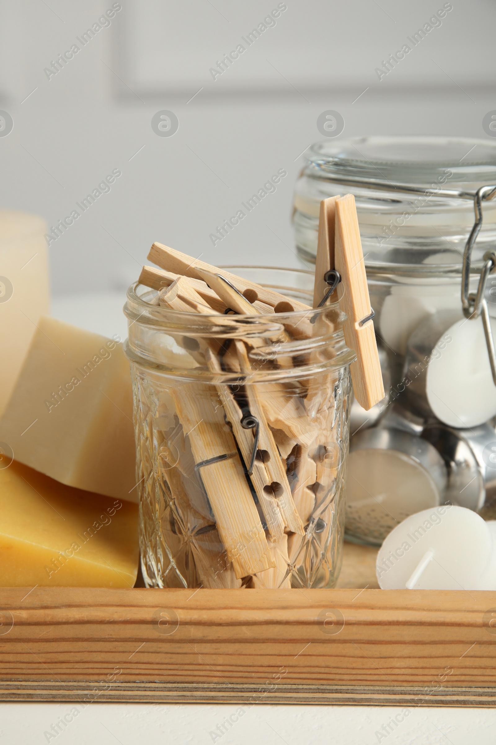 Photo of Many clothespins, candles and soap bars on wooden tray, closeup