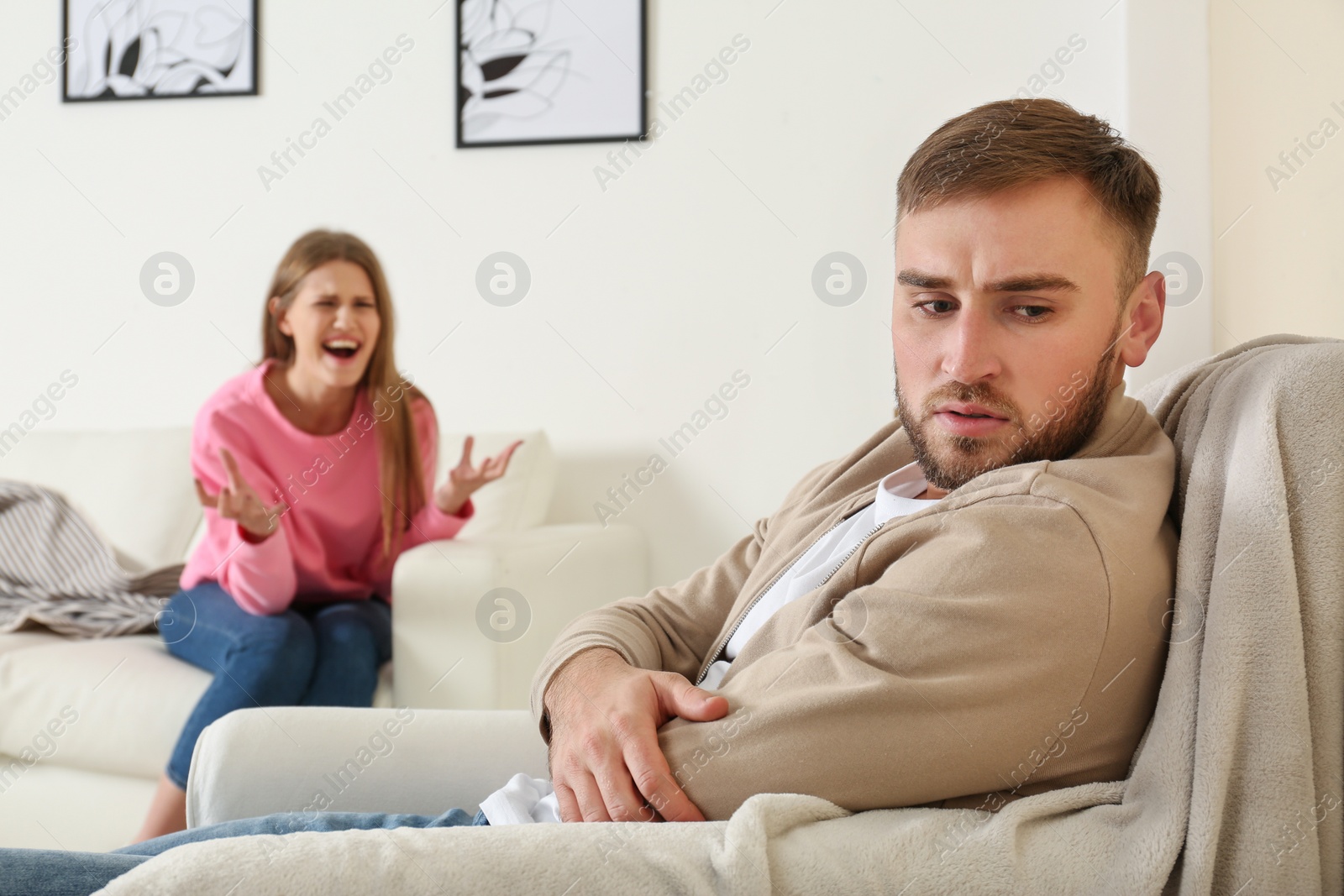 Photo of Young couple having argument in living room. Relationship problems