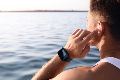 Photo of Man with fitness tracker after training near river, closeup. Space for text