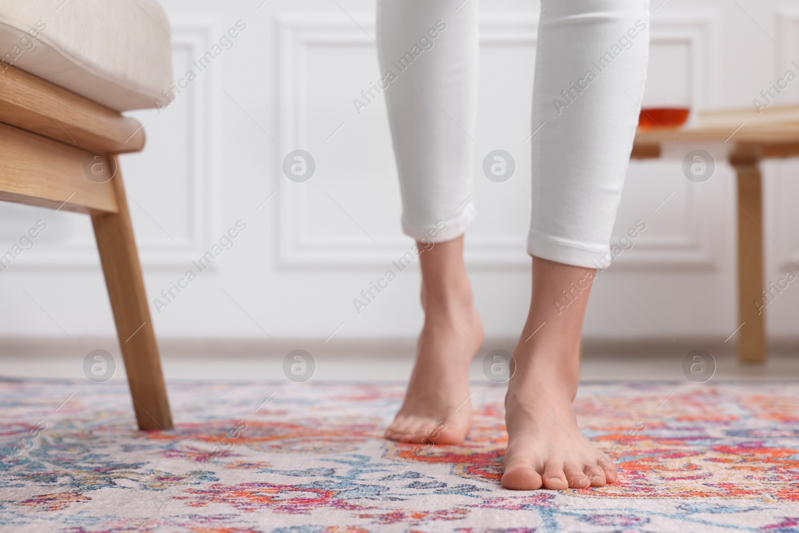 Photo of Woman standing on carpet with pattern at home, closeup