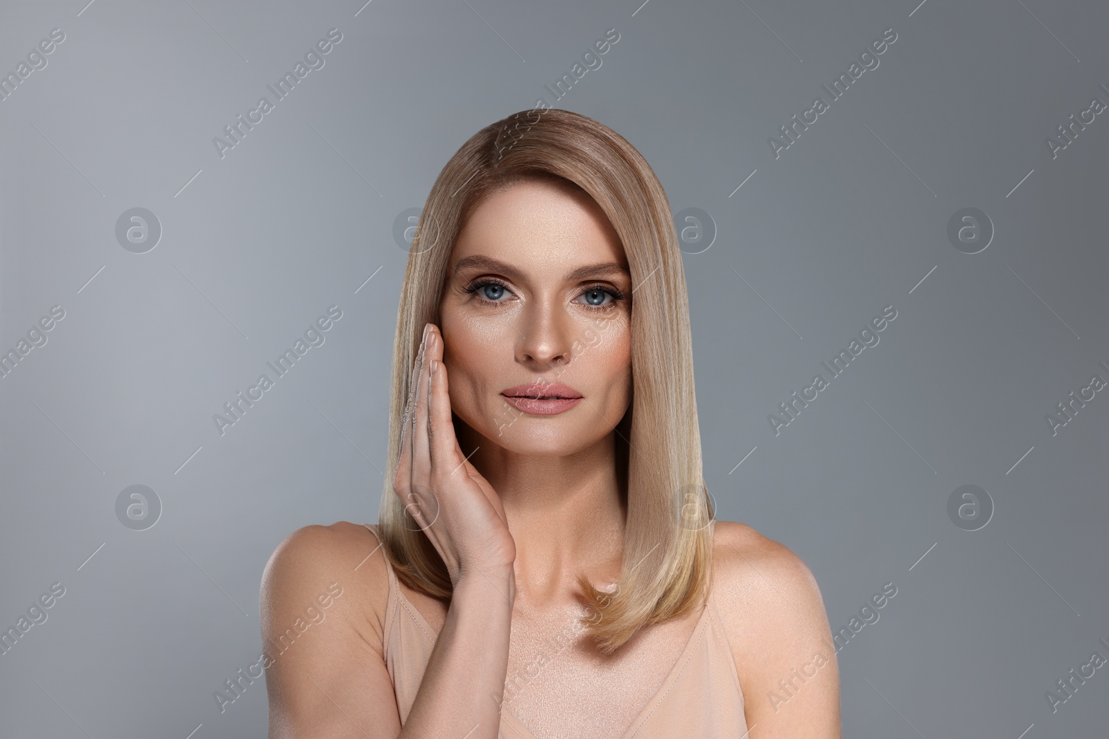 Image of Portrait of attractive woman with blonde hair on grey background