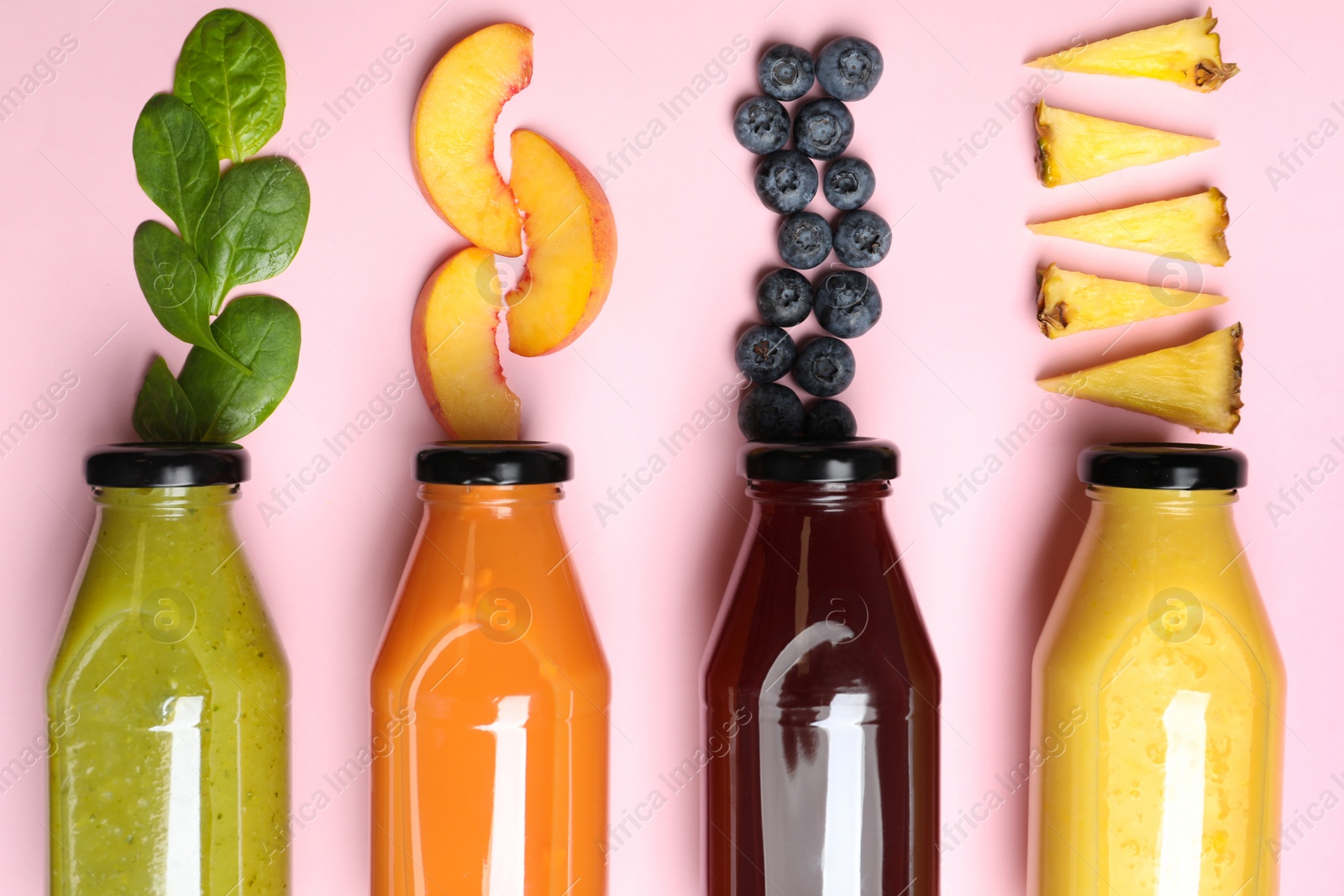 Photo of Flat lay composition with bottles of delicious juices and fresh ingredients on pink background