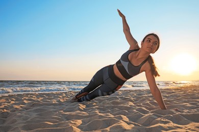 Photo of Young girl with slim body doing yoga on beach