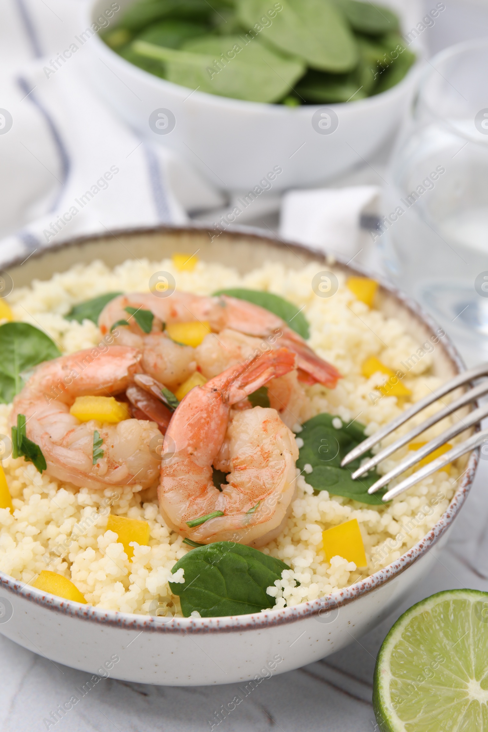 Photo of Tasty couscous with shrimps, bell pepper and basil on white textured table, closeup