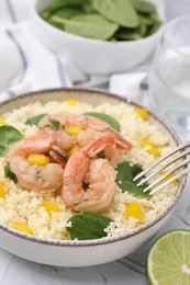 Photo of Tasty couscous with shrimps, bell pepper and basil on white textured table, closeup