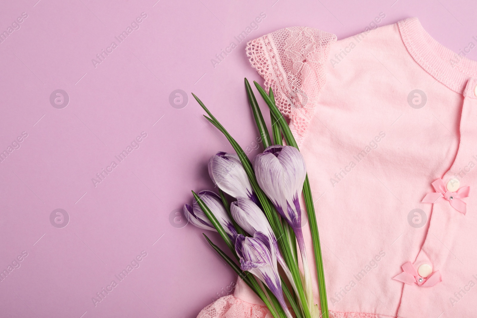 Photo of Child's clothes and flowers on pink background, top view. Space for text