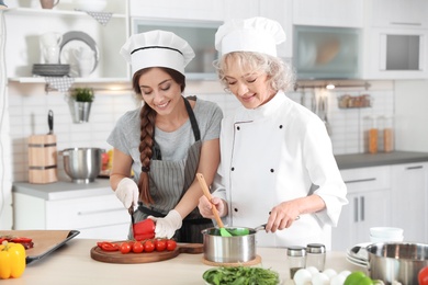 Professional chef and trainee working together in kitchen