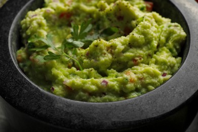 Photo of Mortar of delicious guacamole with parsley, closeup