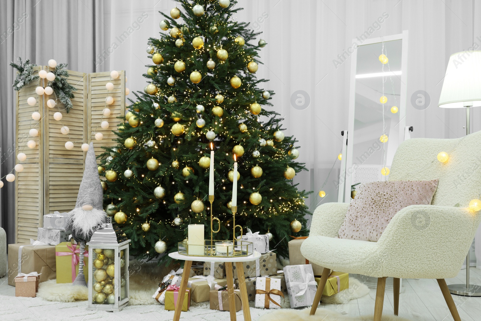 Photo of Beautiful Christmas tree, gift boxes and armchair in festive decorated room. Interior design