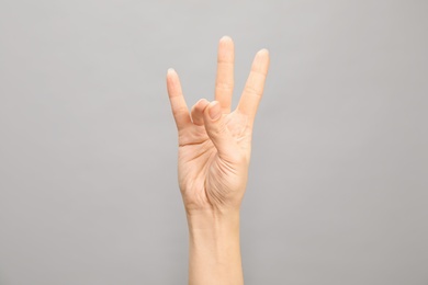 Photo of Woman showing number seven on grey background, closeup. Sign language