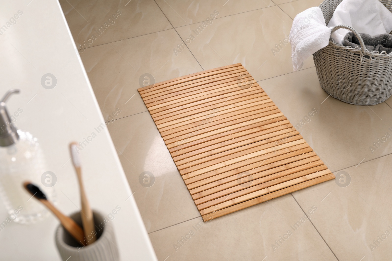 Photo of Wooden mat on floor in bathroom. Interior design