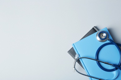 Photo of Student textbooks, stethoscope and space for text on grey background. Medical education