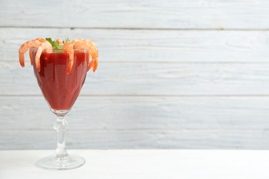 Photo of Shrimp cocktail with tomato sauce on white table. Space for text