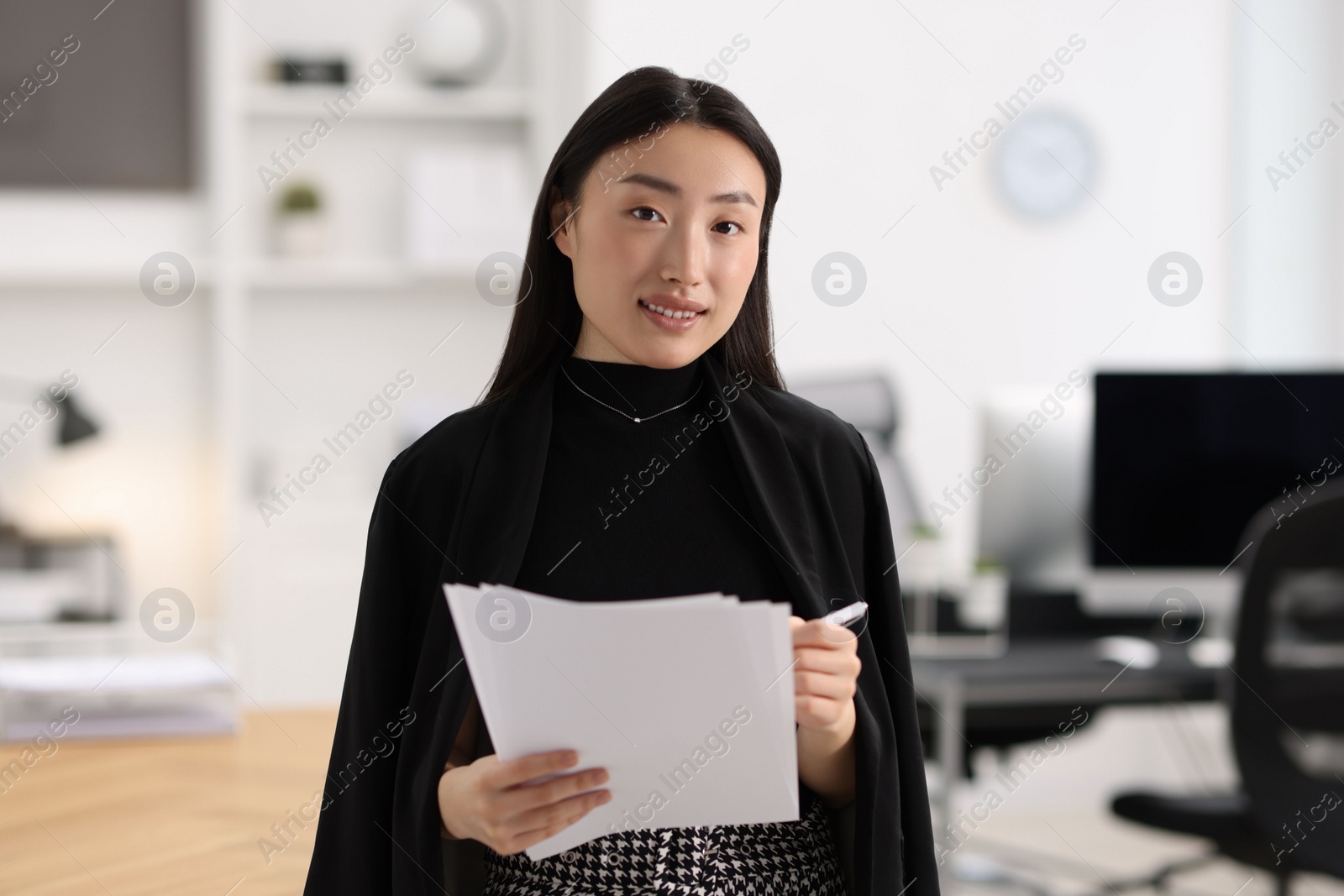 Photo of Portrait of smiling businesswoman with documents in office