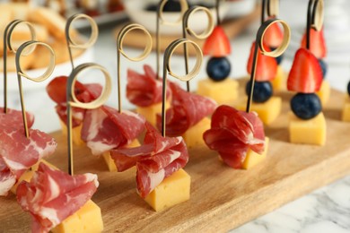 Photo of Different tasty canapes on white marble table, closeup